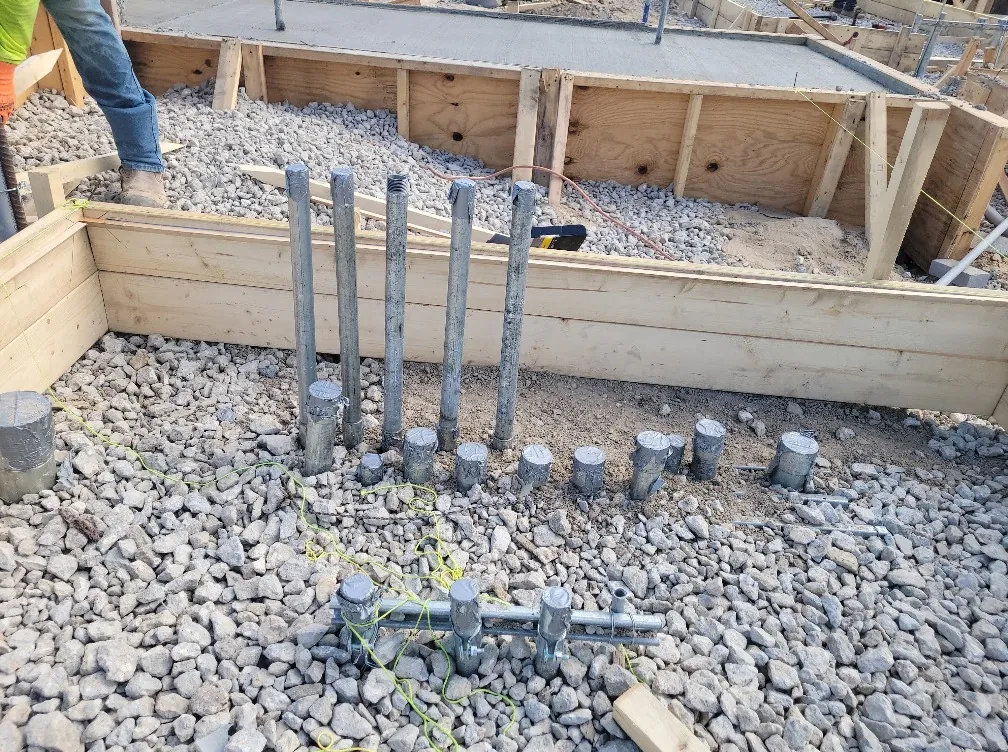 Conduit stubbed up through gravel inside slab forms before the concrete pour