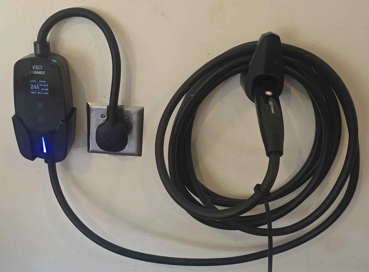 A Level 2 charger on a dedicated 240 volt circuit, its display reading 24 amps at 236 volts