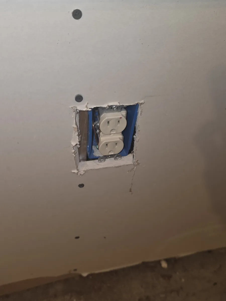 A new receptacle mounted in a fresh box cut into new drywall