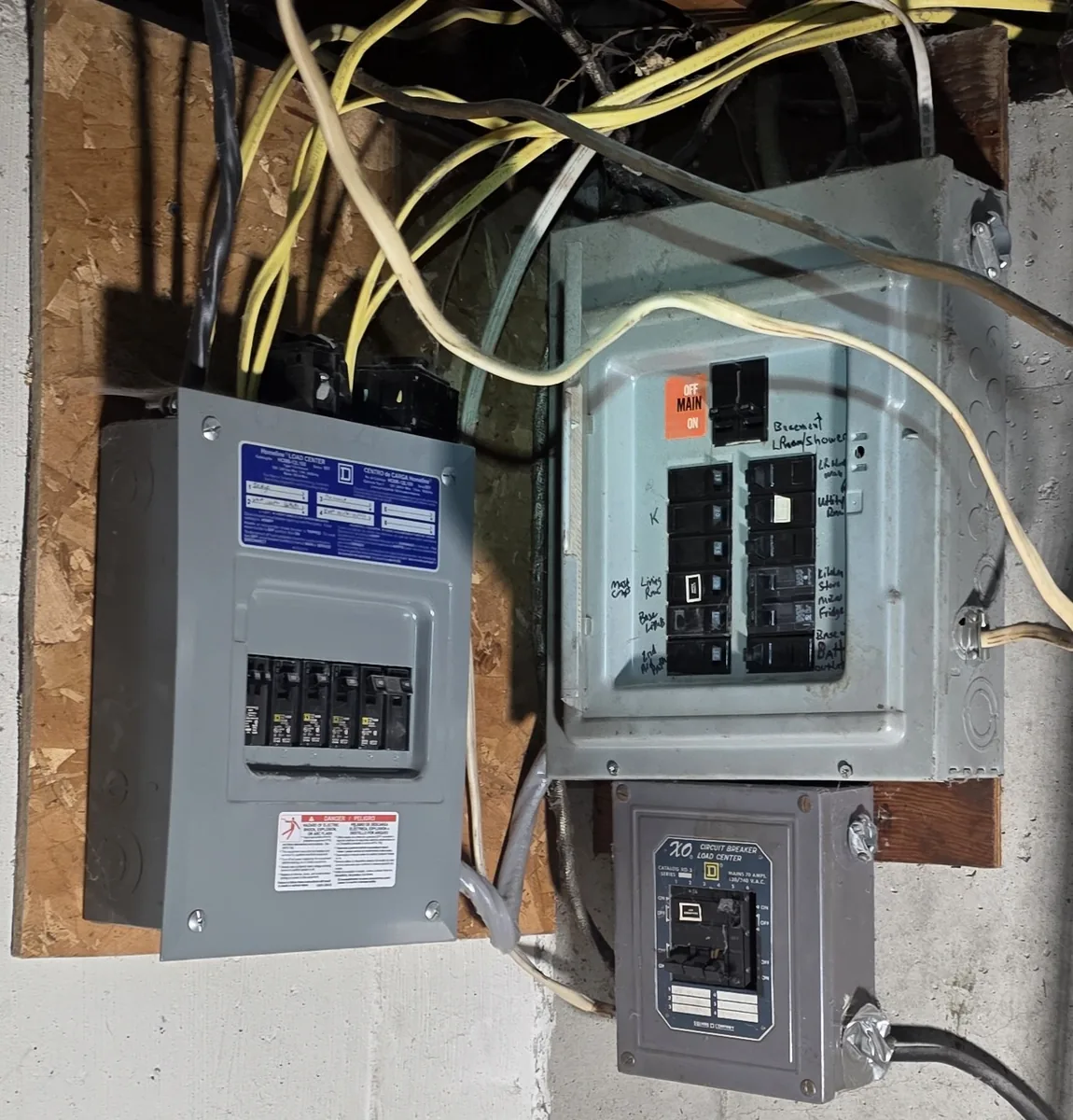 Three separate panel enclosures on one board, circuits labelled by hand in marker
