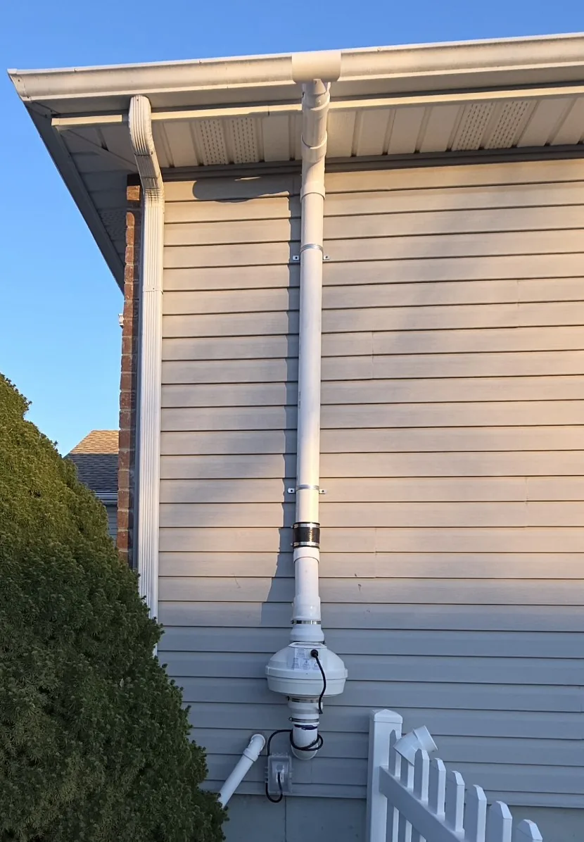 Radon vent pipe running up the outside of a house and discharging above the roofline